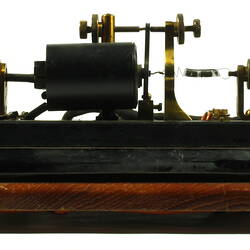 Brass apparatus with batteries on wooden base.