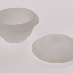 Opaque glass round spice container with lid beside it. Container is narrower at base.