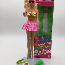 Blonde Barbie doll with box. Wears pink bikini top and skirt and sunglasses. Accessories at her feet.