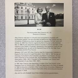 White page with black printed text. Woman and man pose in front of prominent white building, Government House.