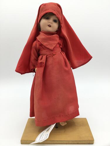A doll dressed in a red gown and long head scarf