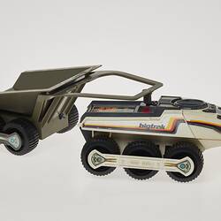 Cream six-wheeled toy truck with grey two-wheeled trailer. Stickers on sides. Right profile.