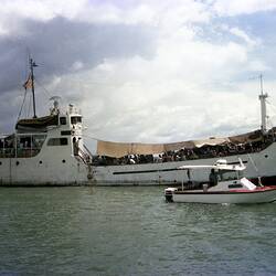 Over-loaded trawler 'Song Be 12' in harbour carrying Vietnamese refugees. Small boat in foreground.
