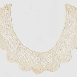 Semi-circular cream lace collar with a waterlily design. Scalloped edges.