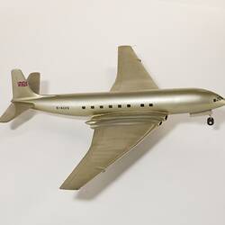 Silver model aeroplane, four wheels beneath each wing and two front wheels. British flag painted on tail.