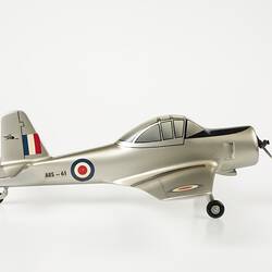 Model aeroplane, silver with black propeller and wheels. Red, white, blue roundels on wings, body and flag on tail.