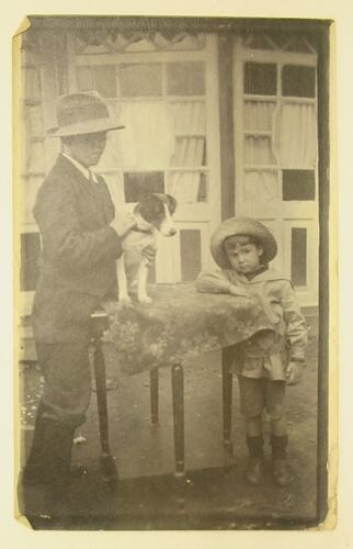 Boy with young man who is holding a dog on a table.
