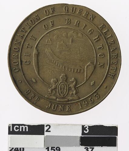 Round medal with coast, pier and ships, text surrounding.