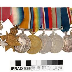 Group of eight medals mounted in a row, with multicoloured ribbons attached to top of medals.