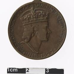 Round bronze coloured medal with profile of a crowned woman, text surrounding.