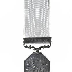 Silver octagonal medal suspended from silver bar attached to white ribbon. Has men with ship.