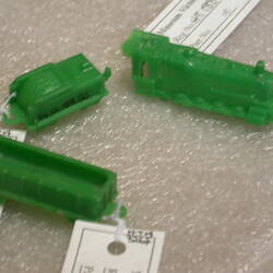 Three green plastic toy trains with white labels.