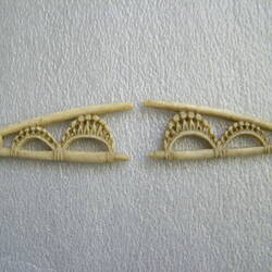 Two white v-shaped ivory pieces that could once have been connected. Both have two decorative crescents within