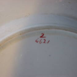 Underside of white dinner plate with red lettering.
