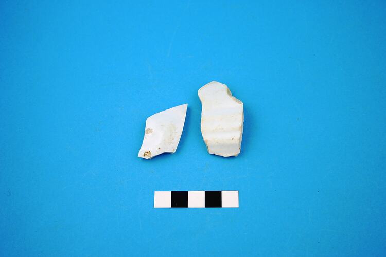 Two broken pieces of white earthenware.