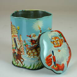 Tin with Christmas motifs, with lide beside.