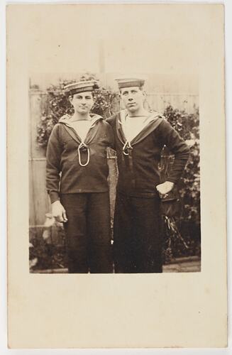 Two men in Navy uniforms standing in a garden.