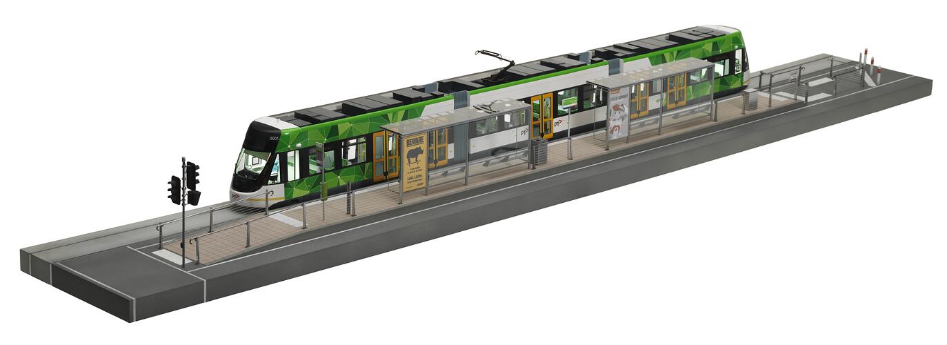 Model of green and white articulated, low-floor tram design set in tram stop.