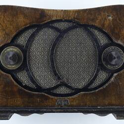 Curved wooden radio with two tuning knobs either side of central circular pattern.