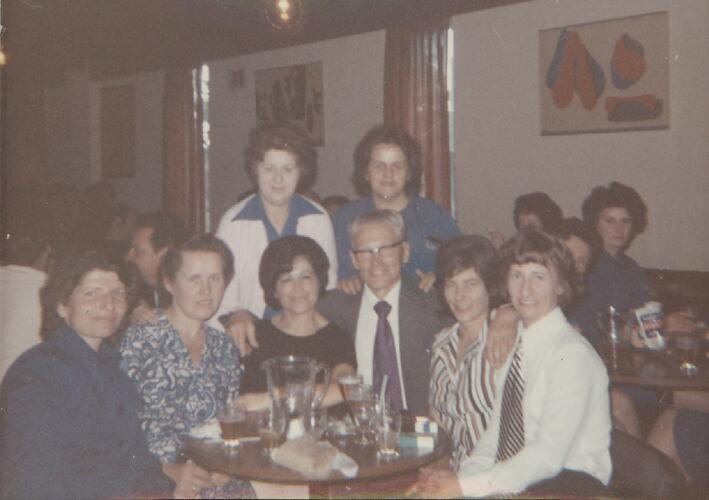 Women gathered around man at dinner table.