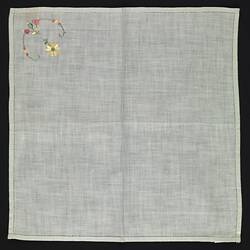 Unfolded green cotton handkerchief with embroidered flower.