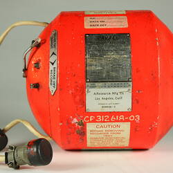 Red cylindrical container with two electrical cords at one end.