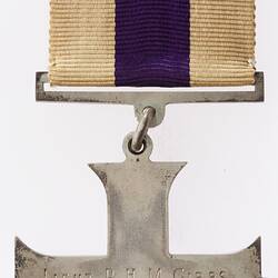 Back of silver cross medal suspended from silver bar on white ribbon with central purple stripe. Metal pin.