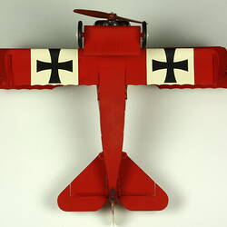 Red aeroplane model. White strip on top of wings with black cross. Underside view.