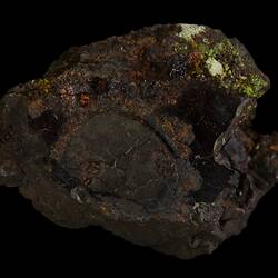 Brown rock with red, orange and green surface coating.