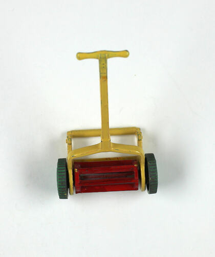 Toy lawn mower with yellow handle.