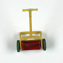 Toy lawn mower with yellow handle.