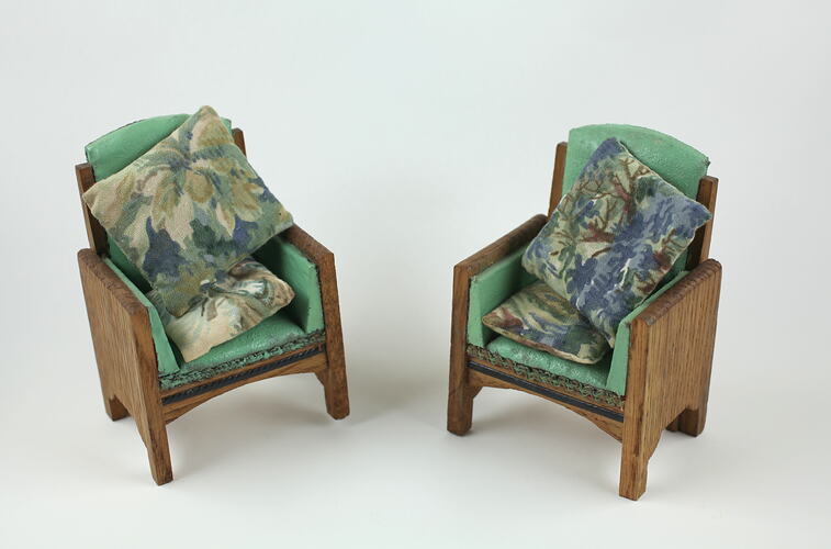 Two toy green armchairs with cushions.