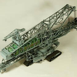Grey plastic mining machine on caterpillar wheels, three quarter view.