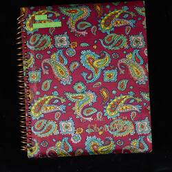 Pink album, ring bound with colourful paisley pattern. Green label top left corner.