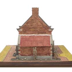 Model of red brick cottage and garden made from icing.
