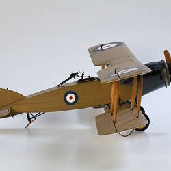 Model biplane aeroplane painted mustard brown with grey engine. Right side view.