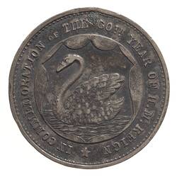 Round tarnished silver-coloured medal with swan facing left in water, text around edge.