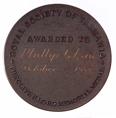 Round medal with text around edge and central engraved text.
