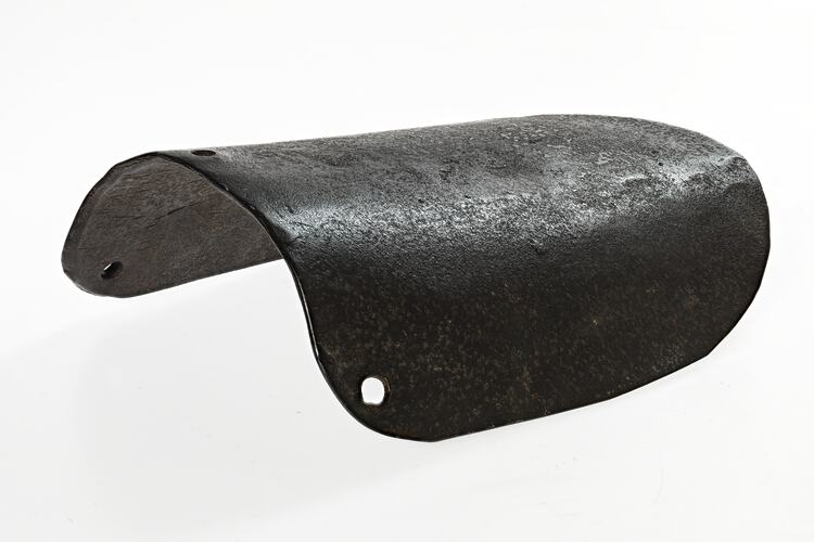 Curved brown metal section of metal with small punched holes at one end.