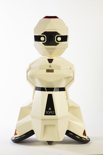Cream plastic robot with angular human-like shape, ie. head, shoulders, waist and legs. Black plastic features.
