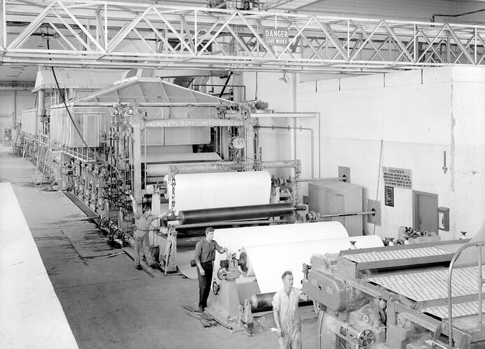 Three men operating paper press machines.