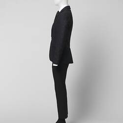 Left profile view of black suit made of textured black and grey wool blend fabric, Two pockets.