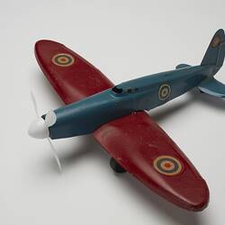 Blue and red toy aeroplane, left, front, three-quarter profile.