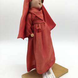 A doll dressed in a red gown and long head scarf