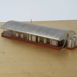 Model of a house with an arched roof, corrugated iron and wide expanses of glass.