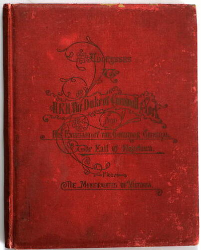 Hard-covered book, red cloth, with gold impressed decorative lettering.