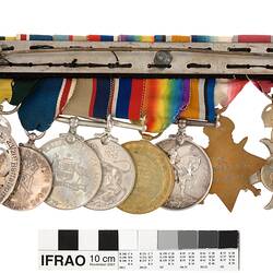 Group of eight medals mounted on a bar, with multicoloured ribbons attached to top of medals.