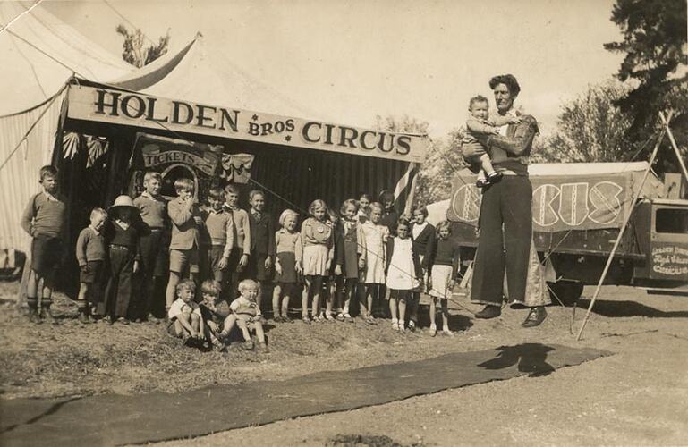 Digital Photograph - Holden Brothers Circus, Man Holding Baby while Balancing on 'Slack Wire' with Children Watching, early 1940s