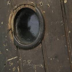 Detail of viewing port in a wooden door.