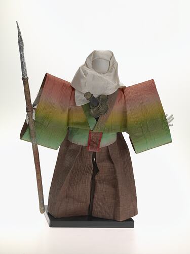 Front view of cloaked paper doll on mount.